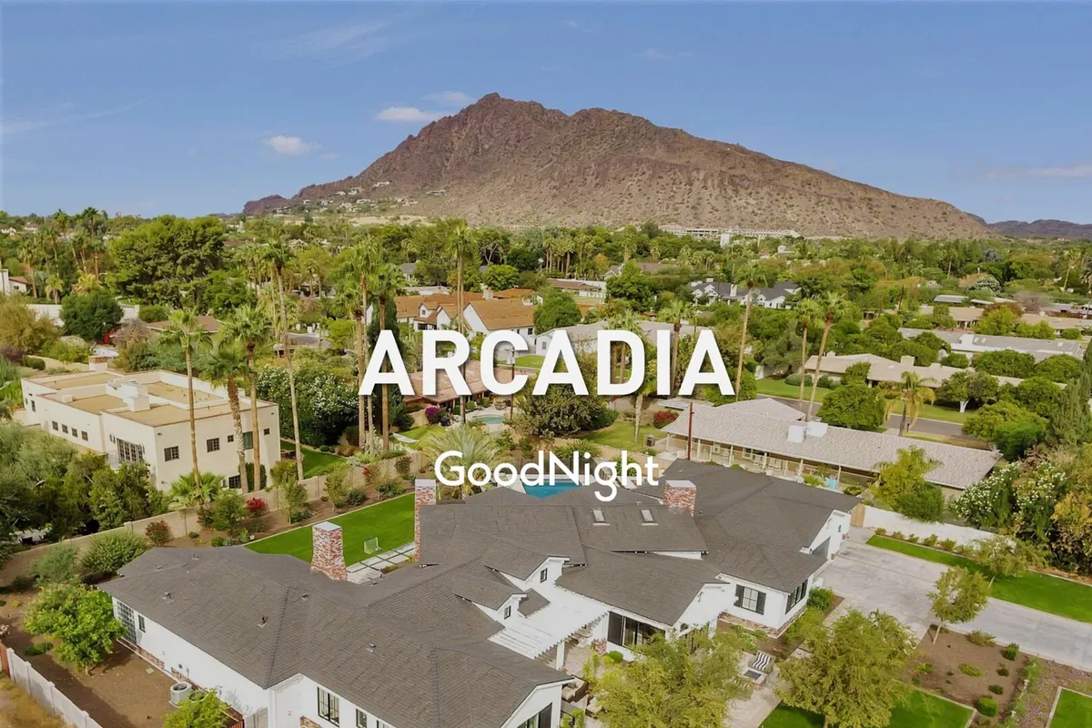 An exterior view showing the architecture of a home surrounded by lush greenery and mountain views in the background. The image conveys the residential and scenic qualities of the community, with visible outdoor spaces hinting at multi-level living.