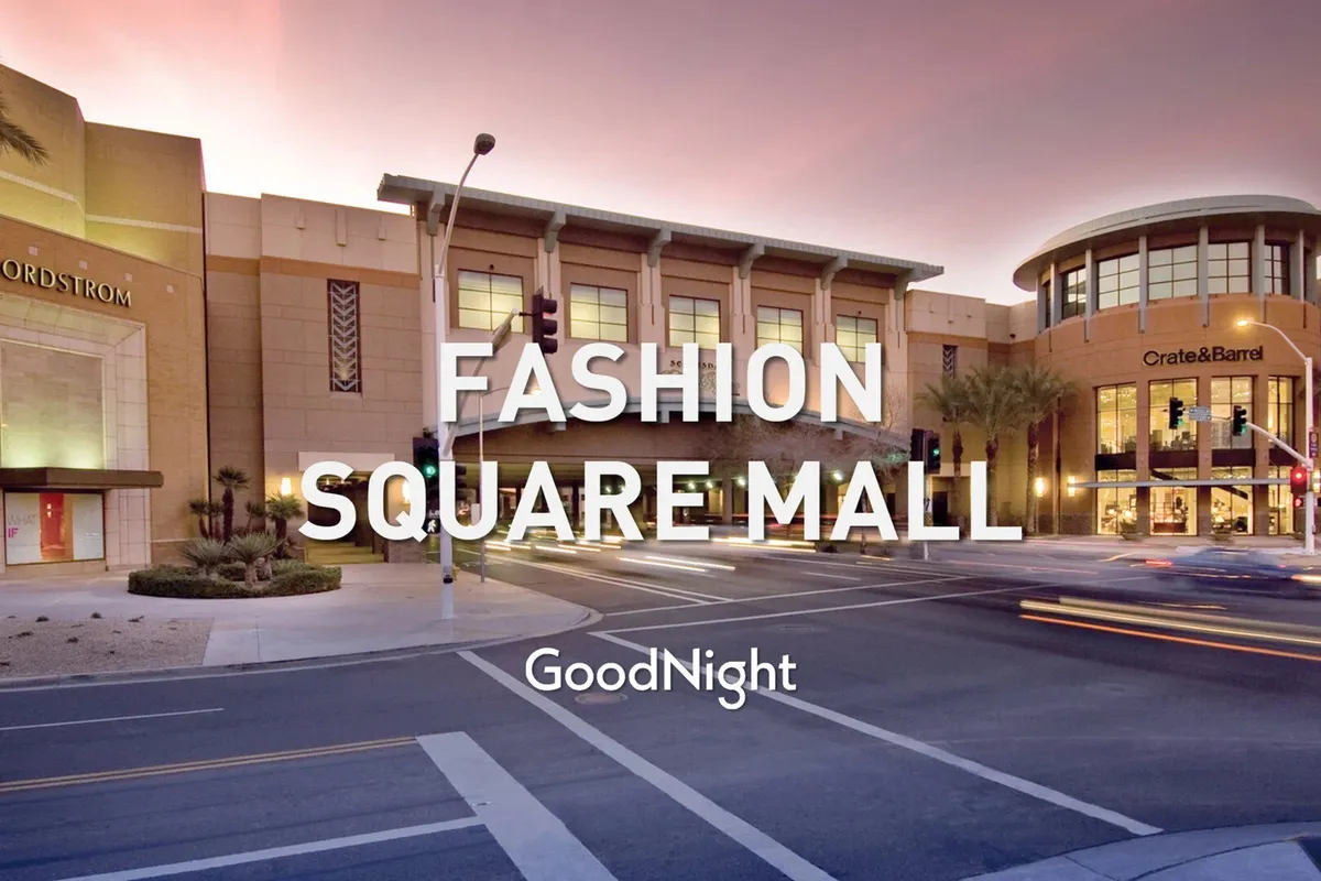 The exterior of the Scottsdale Fashion Square, featuring the Nordstrom and Crate & Barrel storefronts lit up and buzzing with activity. The scene highlights a vibrant street life with people socializing and shopping, capturing the lively spirit of the neighborhood’s premier retail destination.